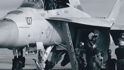 Military fighter jets parked on a flight line with crew members nearby.