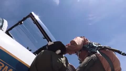 A pilot in flight gear leaning into the cockpit of an aircraft.