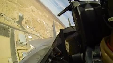 Cockpit view banking left over a desert landscape.