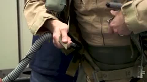 Person adjusting and buckling harness equipment on a flight suit.