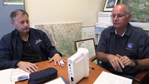 Two men sitting at a table discussing medical equipment together.