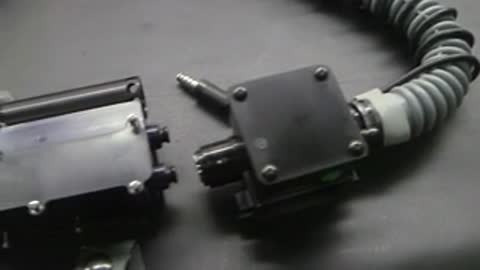 Close-up view of mechanical connectors and hoses on a dark surface.