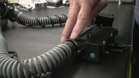 Hands pointing at breathing apparatus hoses and connectors on a table.