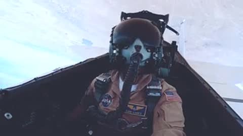 Pilot in cockpit wearing helmet and oxygen mask during flight.