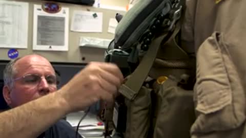 Hands adjusting equipment on tactical vest.