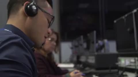 Man working at computer terminal in control room.