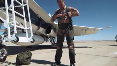 Pilot preparing and adjusting gear next to jet fighter.