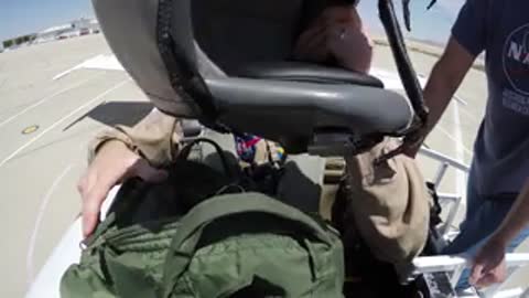 Pilot settling into cockpit of fighter jet.