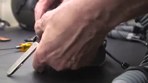 Hands working on equipment parts on workbench.