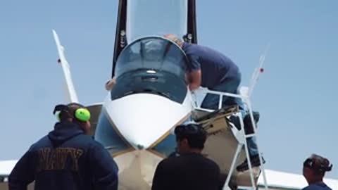 Ground crew working on cockpit of fighter jet on tarmac.