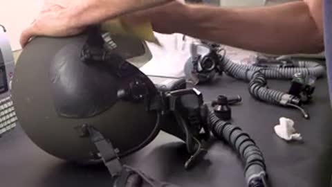 Hands cleaning helmet visor with cloth.