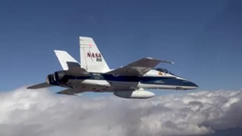 NASA fighter jet flying in formation among clouds.