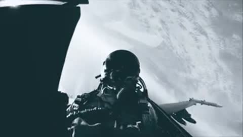 A pilot wearing a helmet inside a fighter jet cockpit, viewed from the front.