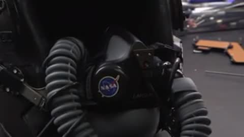 Close-up of a flight helmet with breathing apparatus hoses attached.