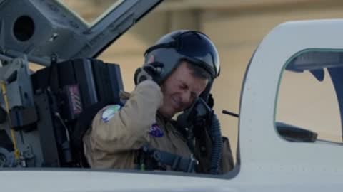 NASA test pilot sitting in X-59 cockpit and putting on helmet.
