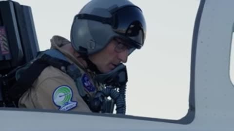 NASA test pilot in X-59 cockpit wearing helmet and glasses.