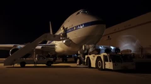 Illustration of a nebula alongside a parked airplane at night on a tarmac.