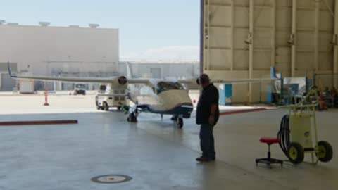 Person walking past the aircraft in the hangar and equipment testing setup