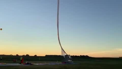 A weather balloon standing upright as it prepares for launch at dawn.