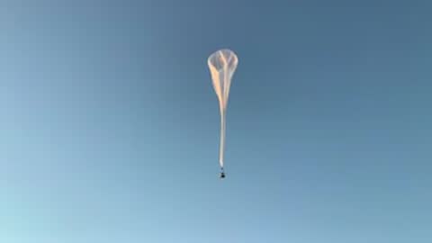 A weather balloon ascending high into the clear blue sky.