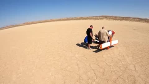 A weather balloon soaring in the sky above a desert landscape.