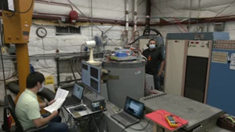 Technician sitting at a desk reviewing documents near testing equipment