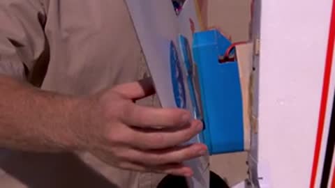Person attaching a blue device to an aircraft wing in a hangar