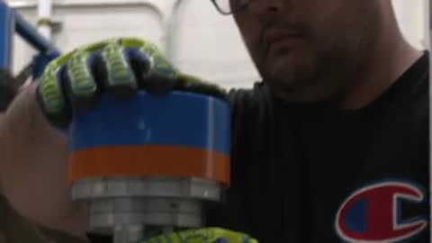 Person wearing gloves assembling a cylindrical mechanical component