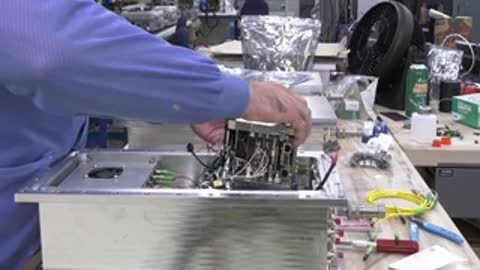 Person working on intricate electrical or computer components inside a housing