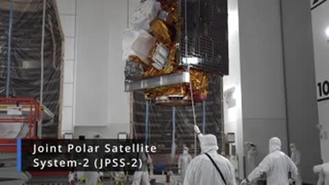 Clean room environment with technicians working near a large satellite structure