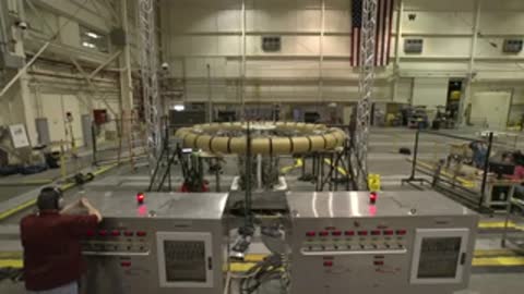 Personnel operating equipment inside a large testing facility hangar