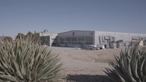 Exterior view of a facility with desert brush in the foreground.