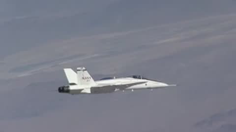 A white fighter jet in flight against a hazy sky background.