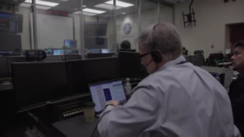 An operator seated at a desk monitoring multiple computer screens.
