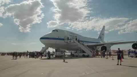 A large airplane sits on an airport tarmac under a cloudy sky.