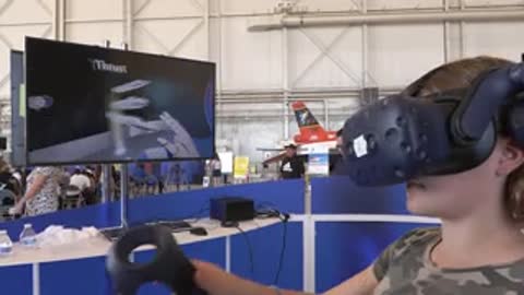 A person wearing a VR headset interacts with a virtual simulation on a screen.