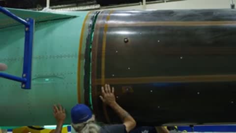 Workers inspecting the fuselage section of the aircraft in assembly