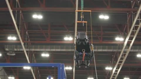 Large aircraft wing in a facility followed by a component being suspended