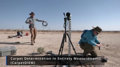Researcher standing near an outdoor acoustic microphone array in a desert landscape.