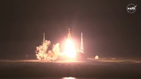 Night rocket launch with bright exhaust plume lighting up the dark landscape
