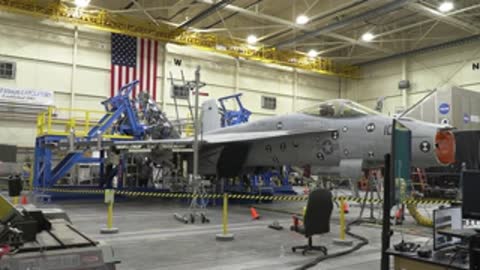 Wide shot of an aircraft undergoing structural testing inside a large testing facility hangar.