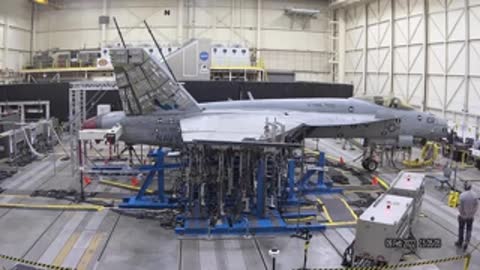 Side view of an aircraft undergoing structural testing in a large industrial hangar facility.