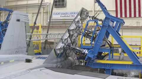 Close-up view of mechanical linkages and actuators attached to an aircraft structure during testing.