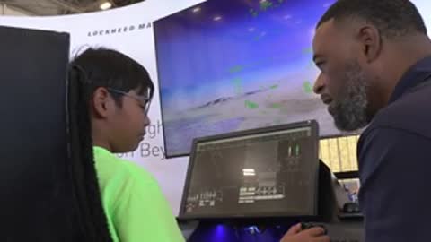 Two people looking at a computer screen displaying digital interface inside a facility