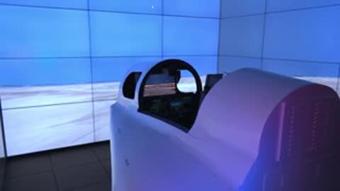 Flight simulator capsule positioned inside a large room with panoramic curved projection screens.