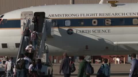 People boarding a NASA Earth Science aircraft via stairs outdoors