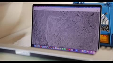 A laptop displays topographical or radar data on its screen.