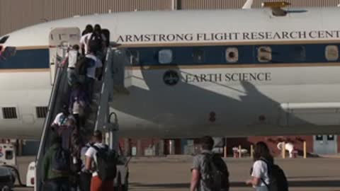 A group of people boards an aircraft via stairs on the tarmac.