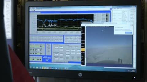 A computer monitor displays sensor graphs inside an aircraft cabin.