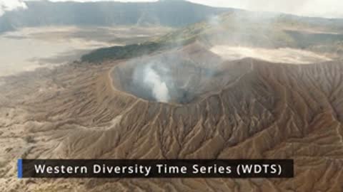 Aerial view of a large volcanic crater with smoke rising from the center.